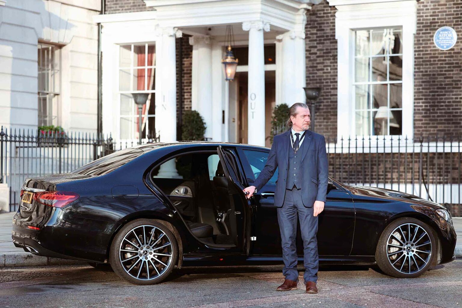 Royal Lane chauffeur assisting a client beside a Mercedes-Benz
